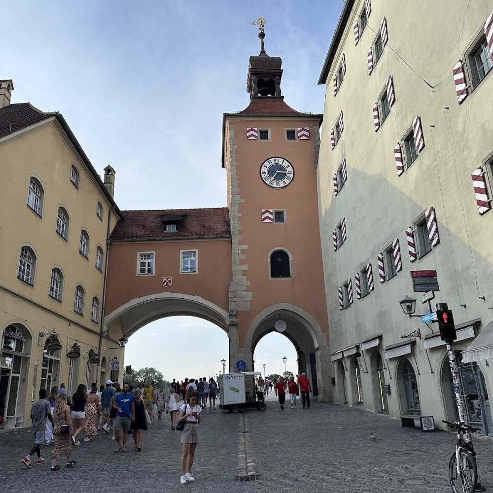 A clock tower, arched passageway and people walking in the Marienplatz in Munich.